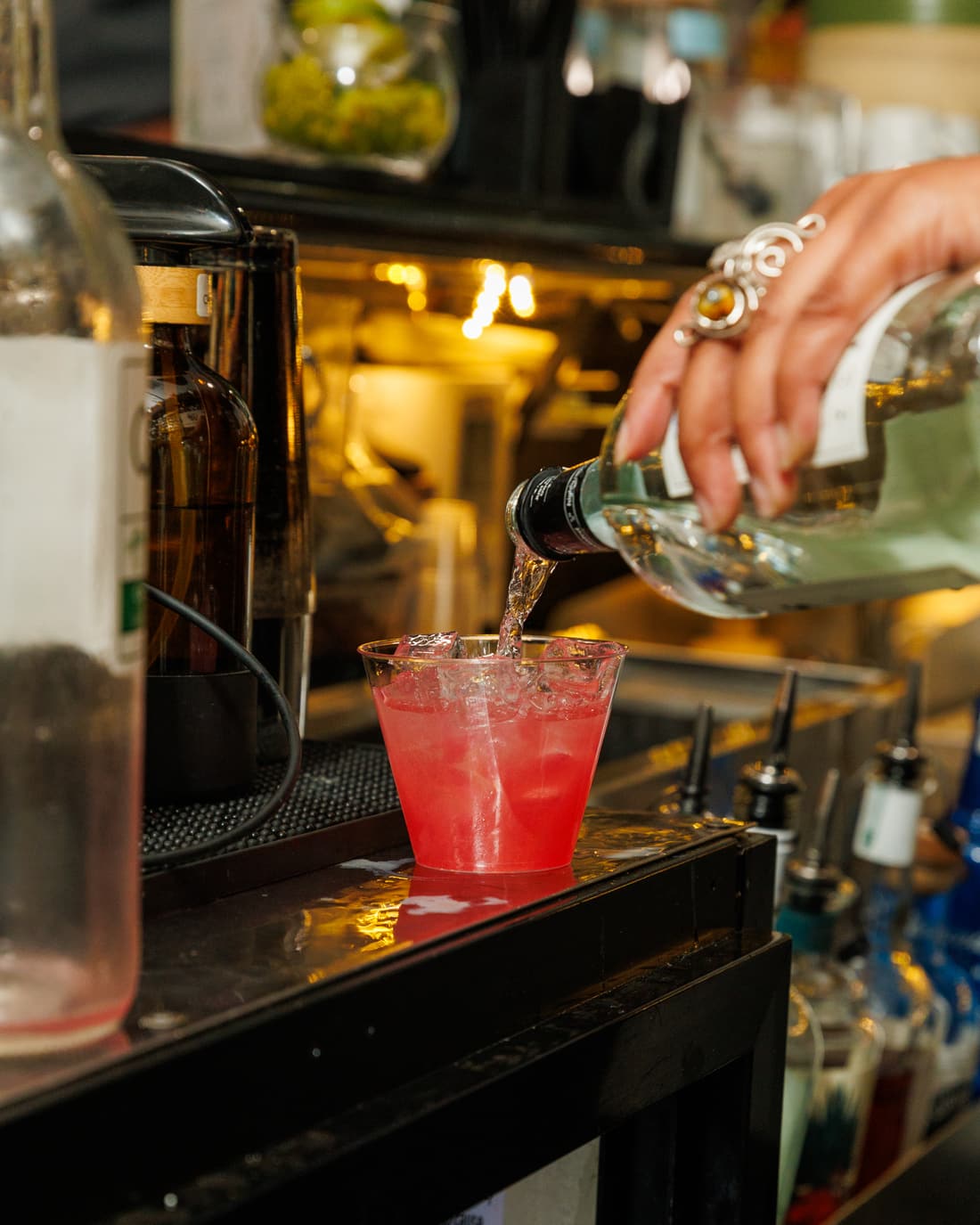 Bartender pouring a red cocktail into a glass at the bar at Stem & Vine in Baltimore