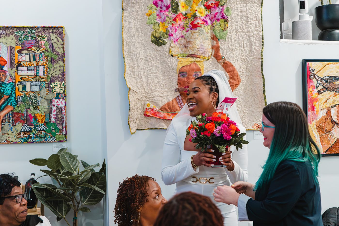 A bride-to-be receiving a bouquet beneath the gallery wall at Stem & Vine, Baltimore