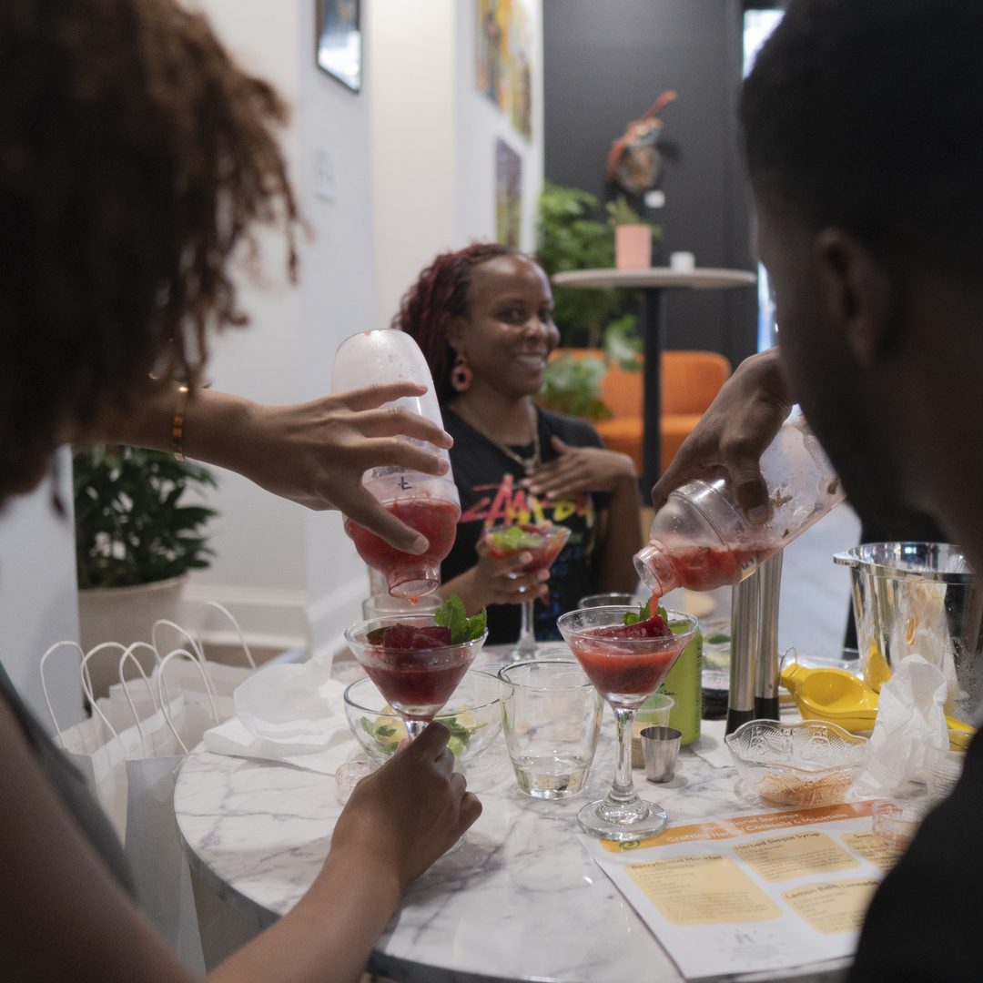 Guests pouring their own red botanical cocktails into coupes at a class in the Gallery at Stem & Vine in Baltimore