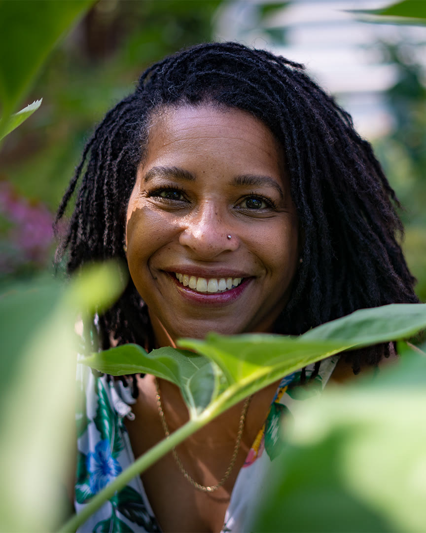 Brittany Williams, herbalist and founder of Eudemonia Herbs, smiling through green leaves