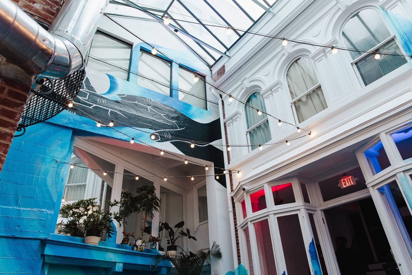 The full skylit courtyard and blue mural inside the historic Browns Arcade at Stem & Vine, Baltimore