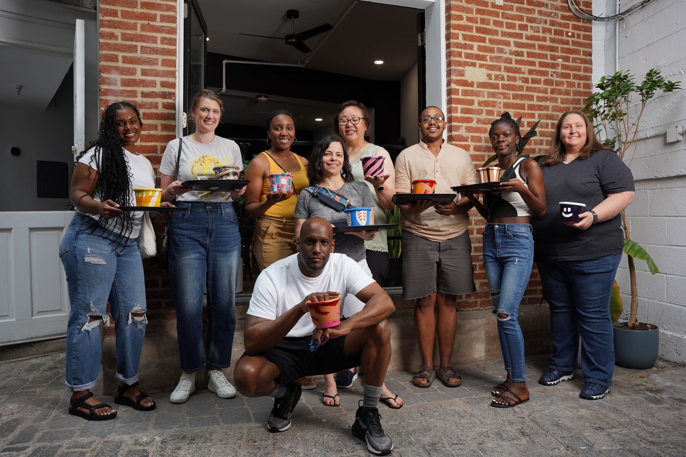 Group of guests posing with drinks in the brick hallway during a full buyout at Stem & Vine, Baltimore