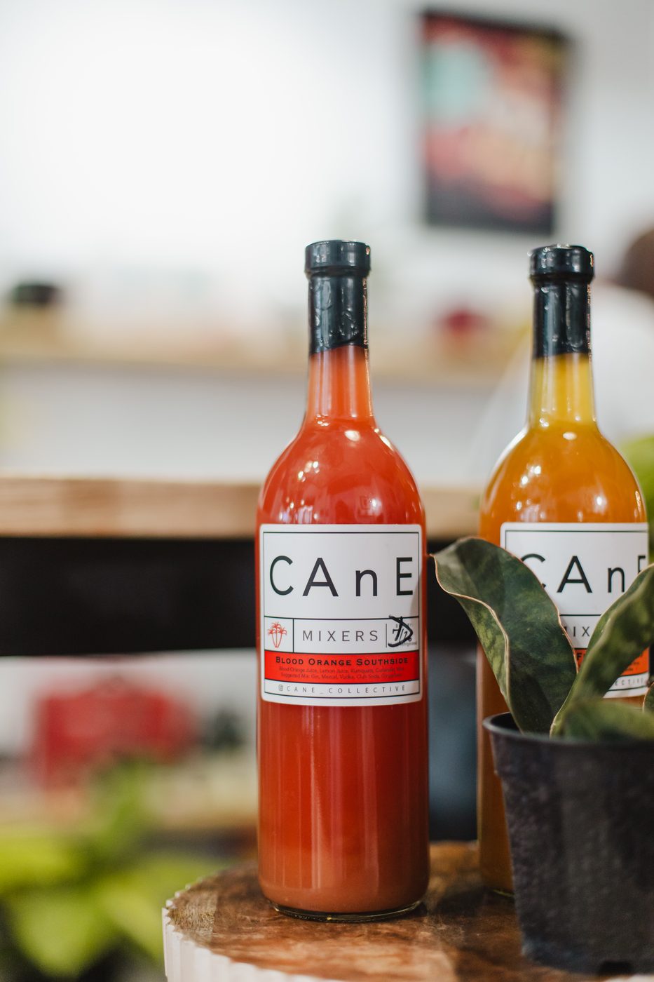 CAnE Mixers bottles, blood orange southside in front, on a table at Stem & Vine in Baltimore