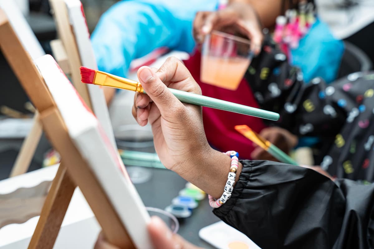 Guest holding a paintbrush to a canvas during a paint session at Stem & Vine in Baltimore