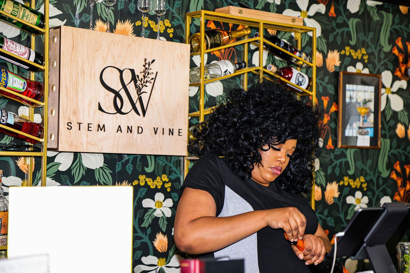 A woman working behind the Botany Bar beneath the Stem & Vine sign during Groove House Radio in Baltimore