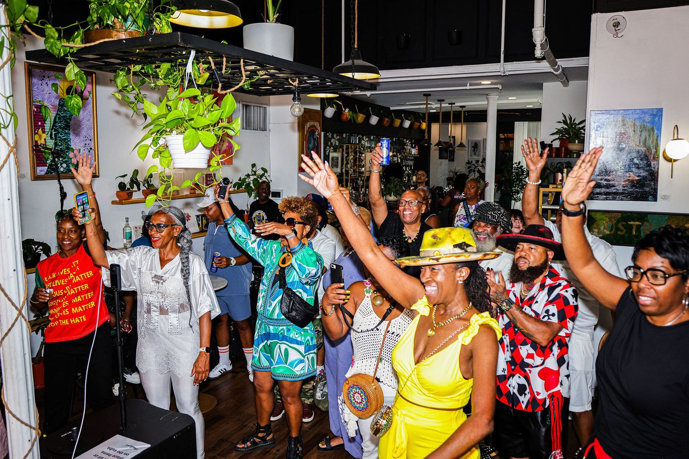Guests raising their hands under the hanging plants during Groove House Radio at Stem & Vine, Baltimore