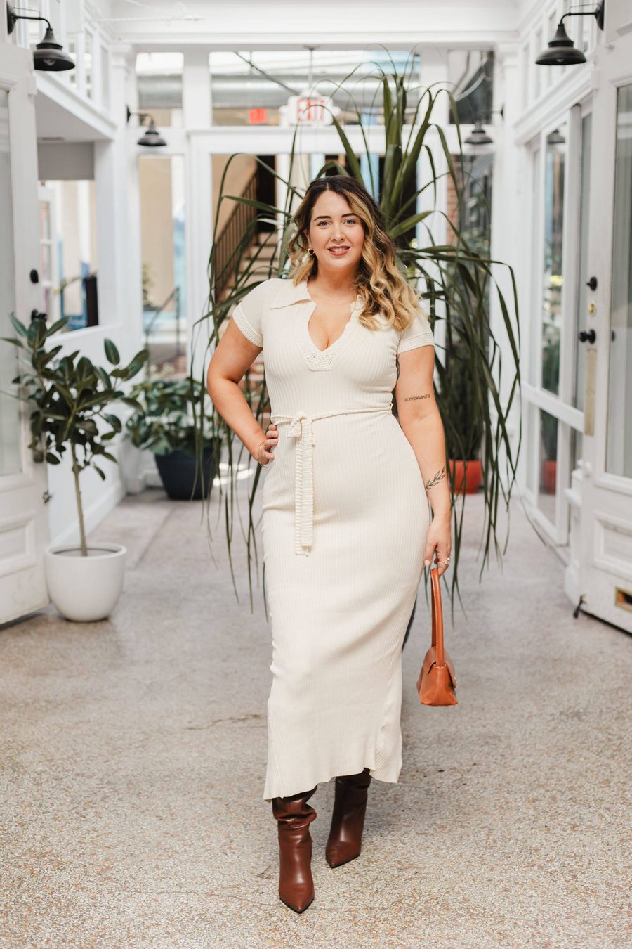 Guest in a white dress walking the plant-lined arcade walkway at Stem & Vine in Baltimore