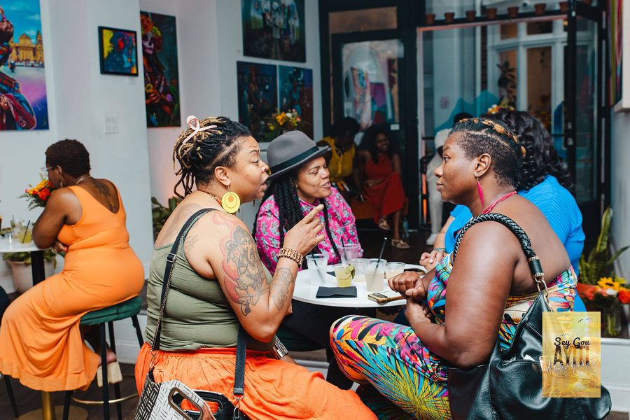 Friends in bright summer colors talking at cafe tables during an event at Stem & Vine in Baltimore