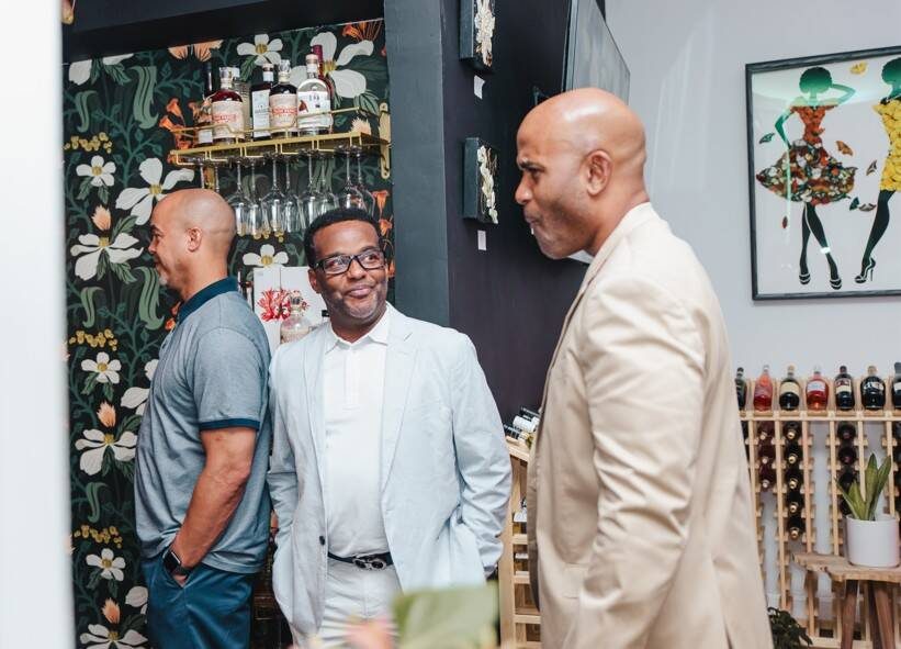 Guests in conversation beside the floral wallpaper and wine racks at Stem & Vine, Baltimore