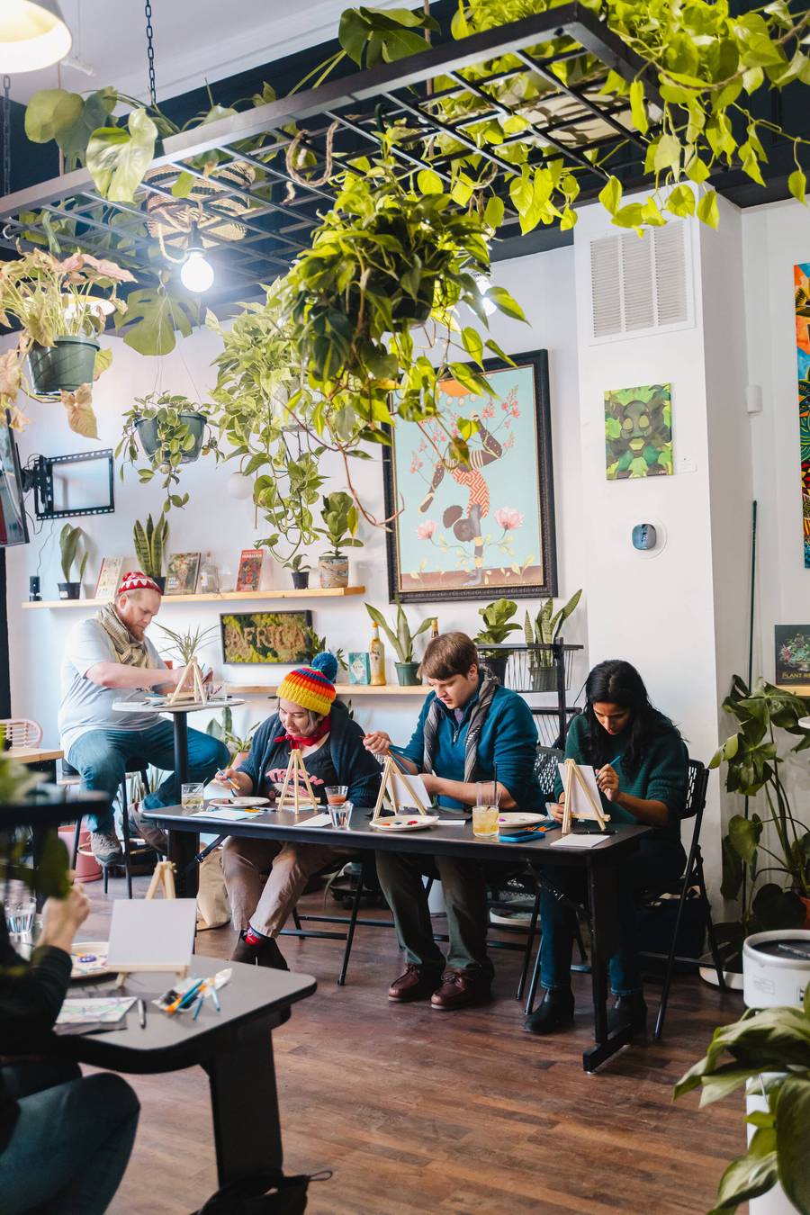 Workshop tables set beneath a canopy of hanging plants at Stem & Vine in Baltimore