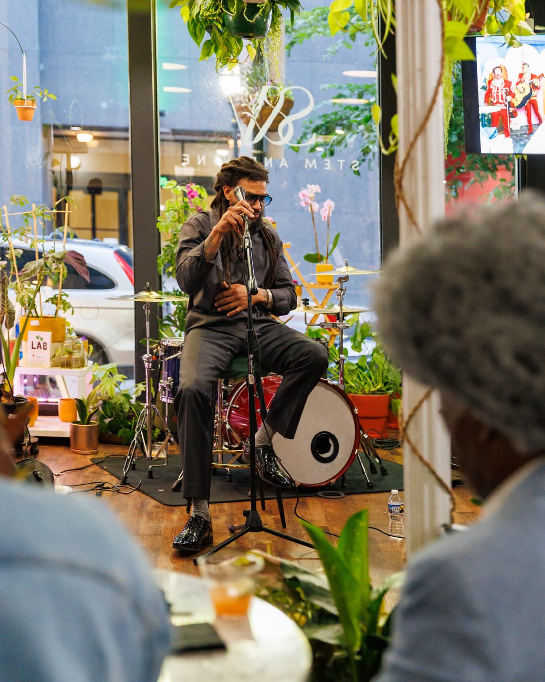 Musician performing beside a drum and the plant shelves at Stem & Vine in Baltimore
