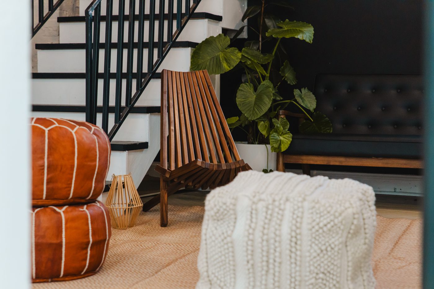 Leather poufs and woven ottomans in the greenhouse lounge beneath the stairs at Stem & Vine, Baltimore