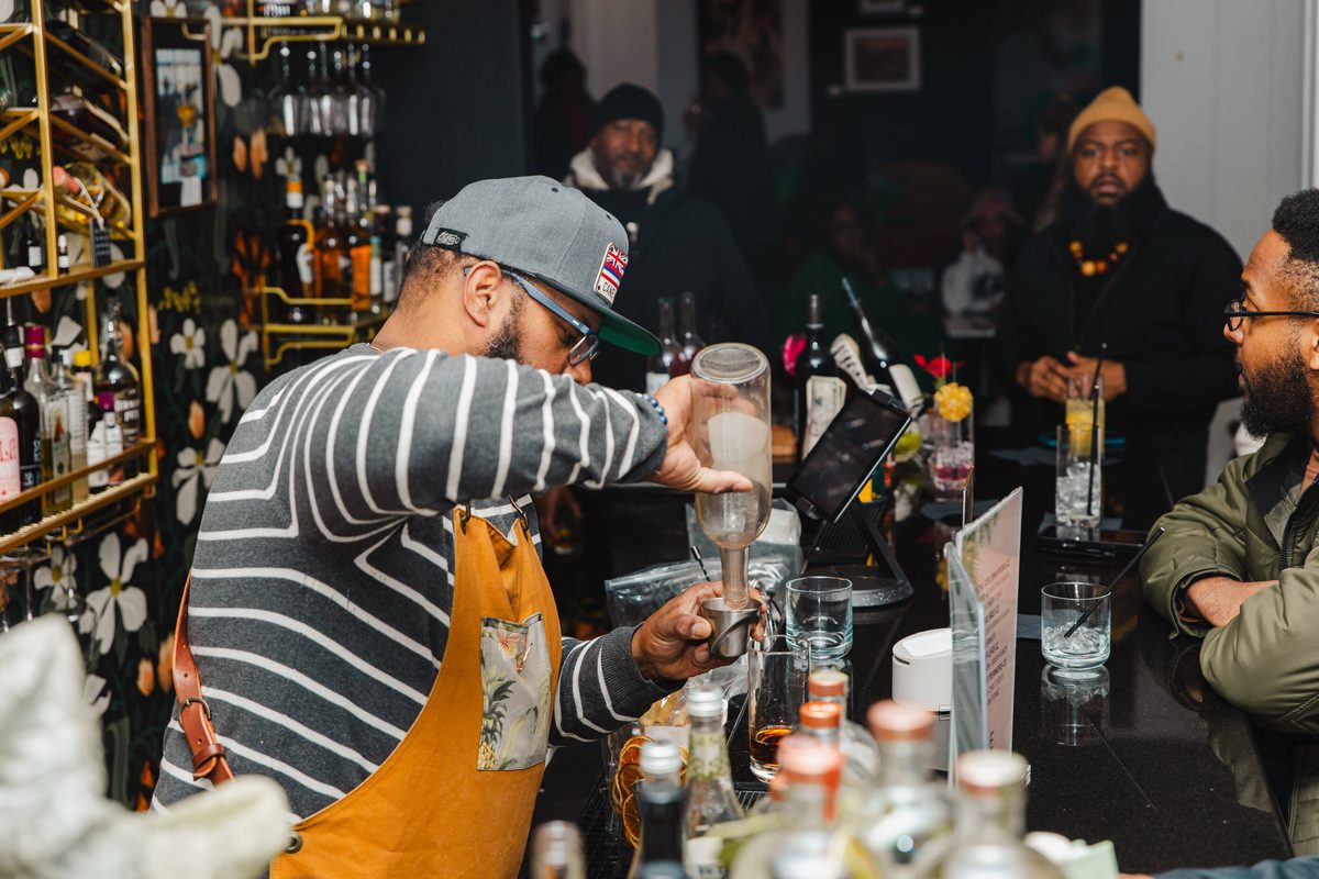 Bartender pouring drinks for a full bar during a tasting event at Stem & Vine in Baltimore