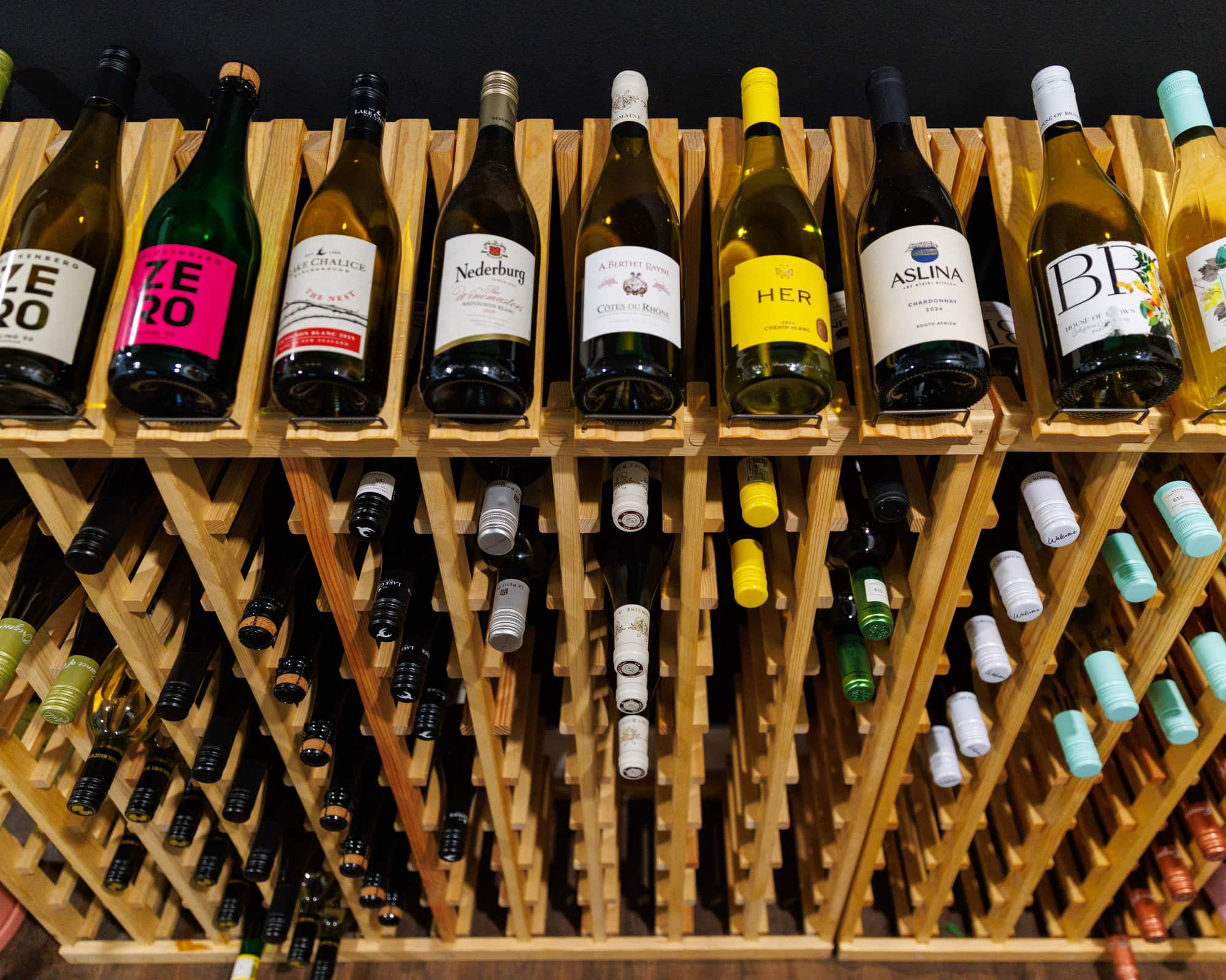 Bottles of wine lying label side out on wooden racks at Stem & Vine in Baltimore