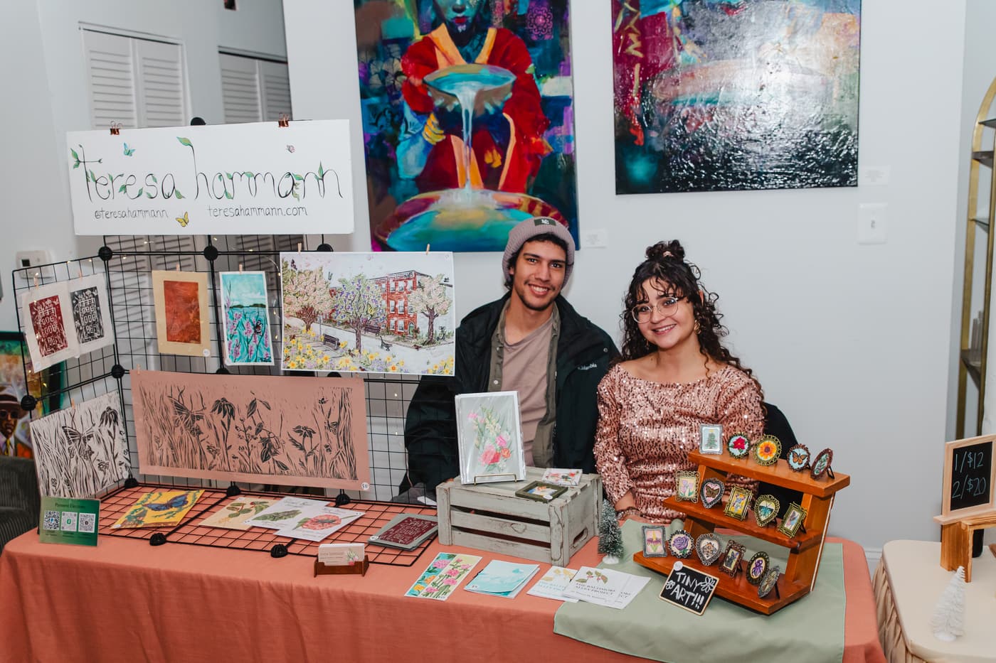 Two vendors behind a table of art prints during a market at Stem & Vine in Baltimore