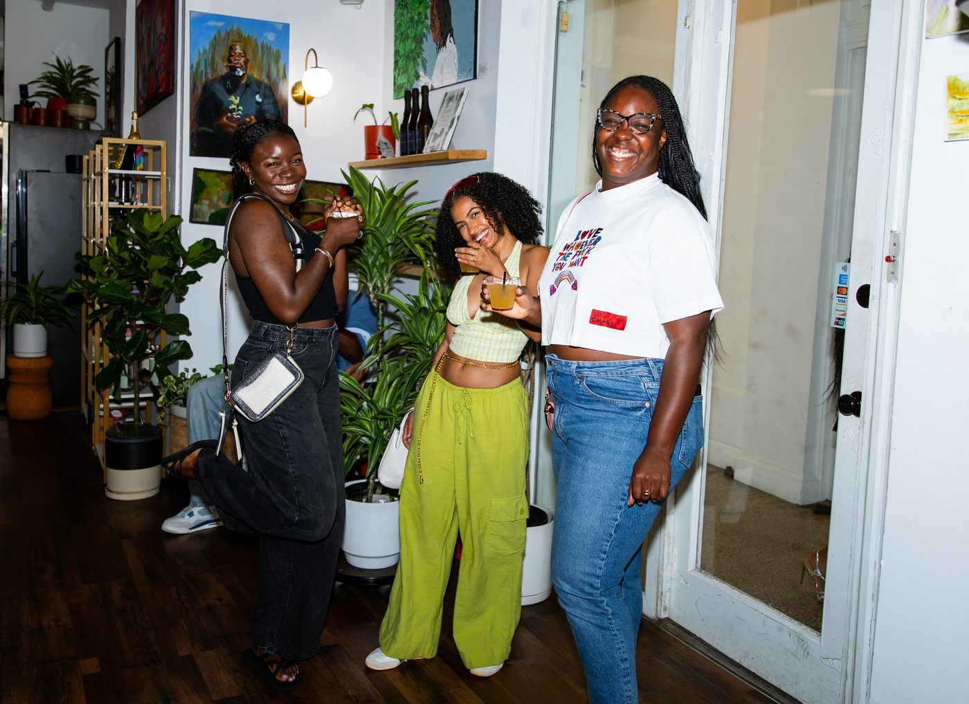 Three friends laughing together among the plants at a party at Stem & Vine in Baltimore