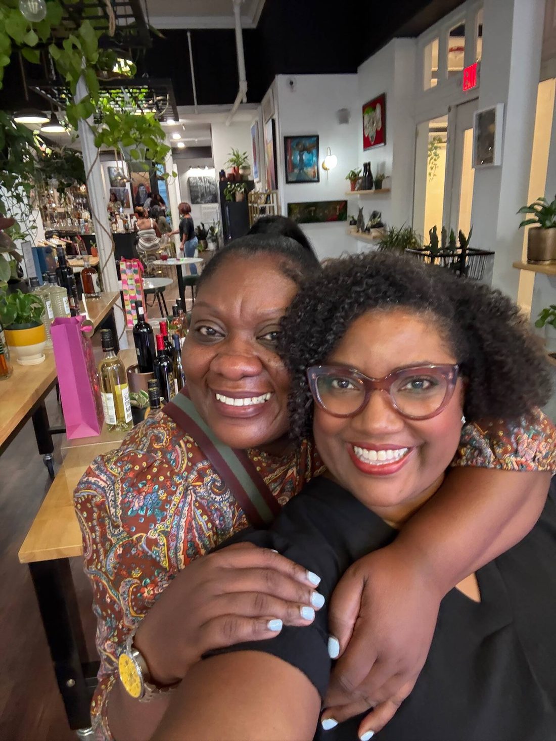 Friends embracing among the plants inside the Stem & Vine shop in downtown Baltimore