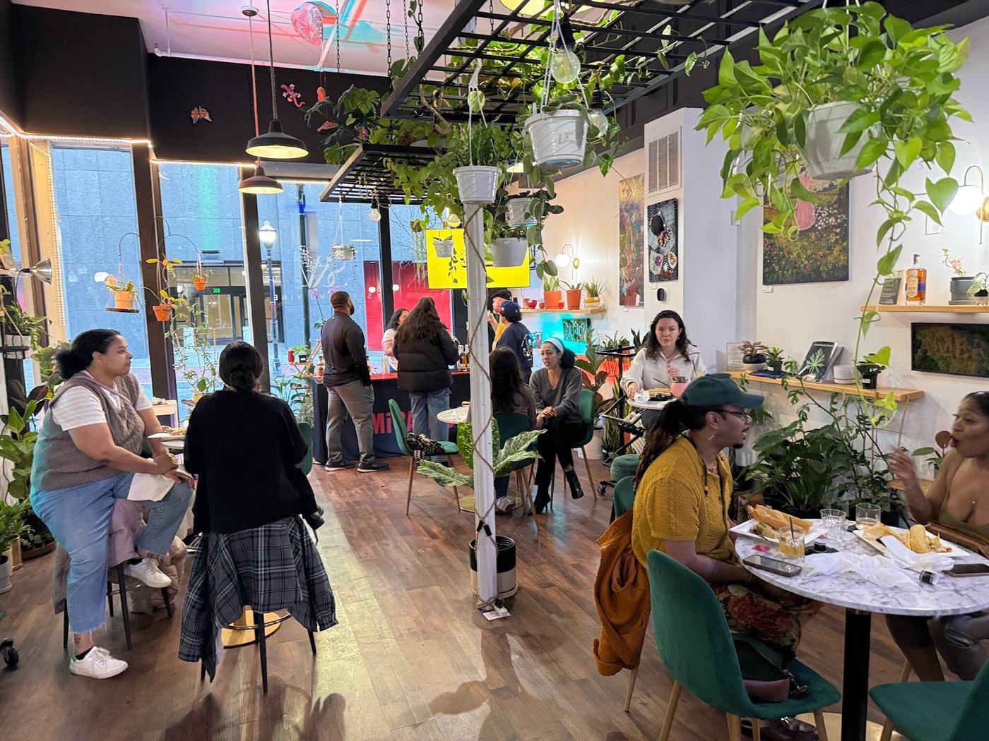 Guests relaxing under hanging plants inside the Stem & Vine plant shop in downtown Baltimore