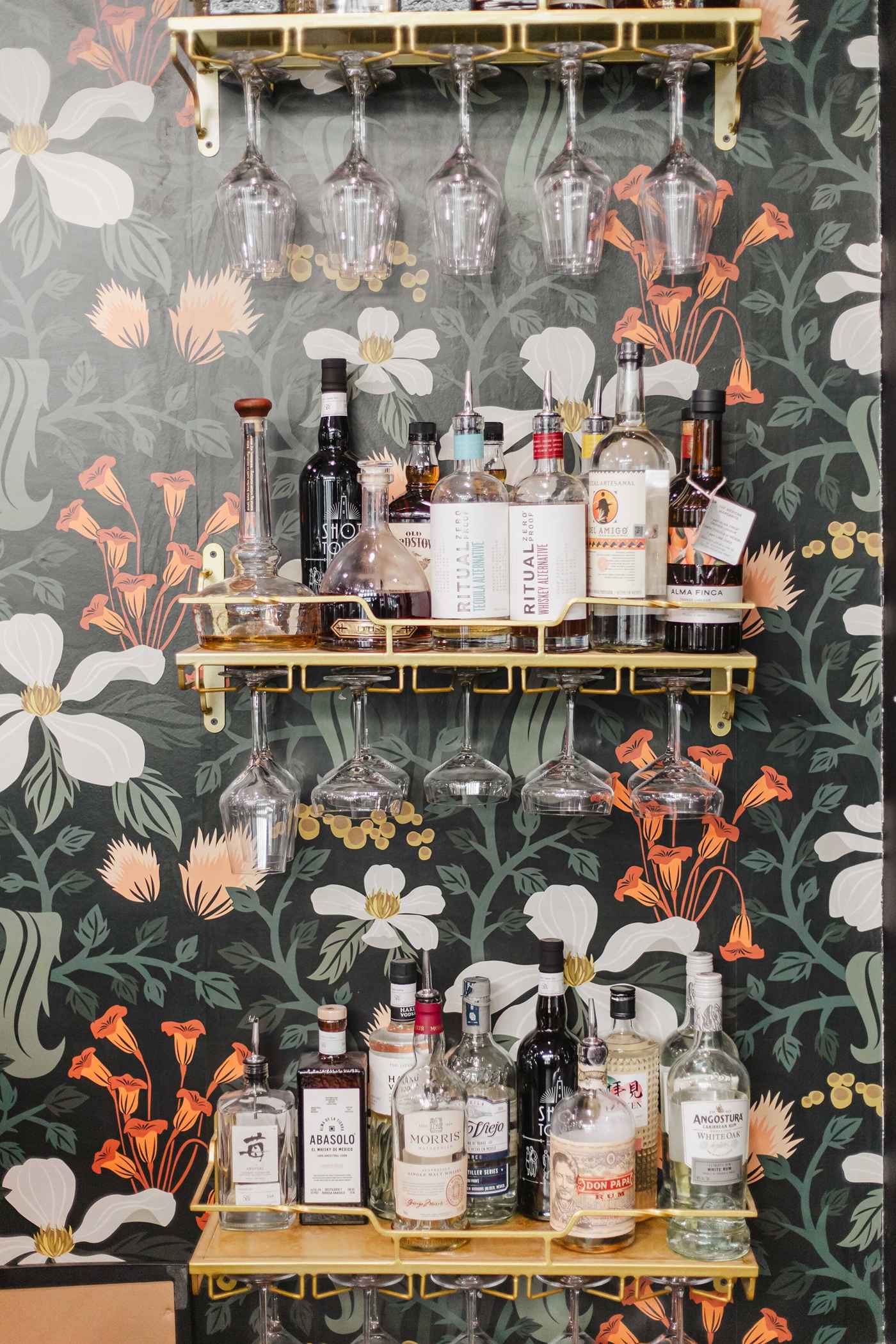 Bottle shelves against the floral wall at the Stem & Vine bar in downtown Baltimore
