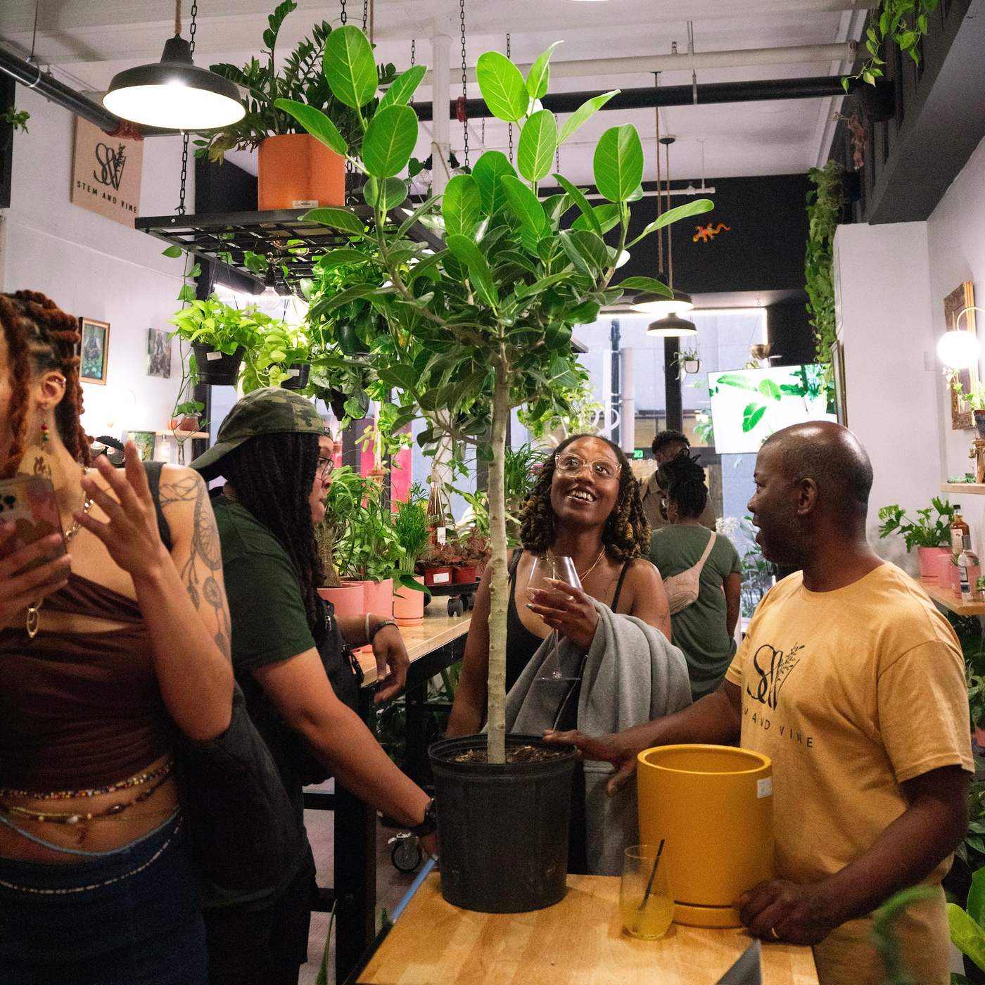 Guests admiring a large plant at the counter inside Stem & Vine, Baltimore