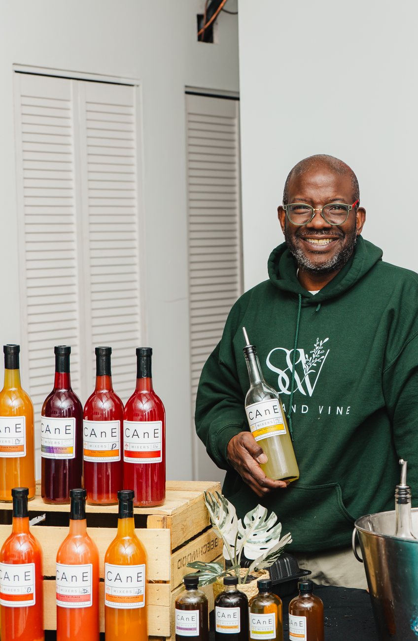 Founder Quincy Goldsmith in a Stem & Vine hoodie behind a table of bottles at the shop in Baltimore