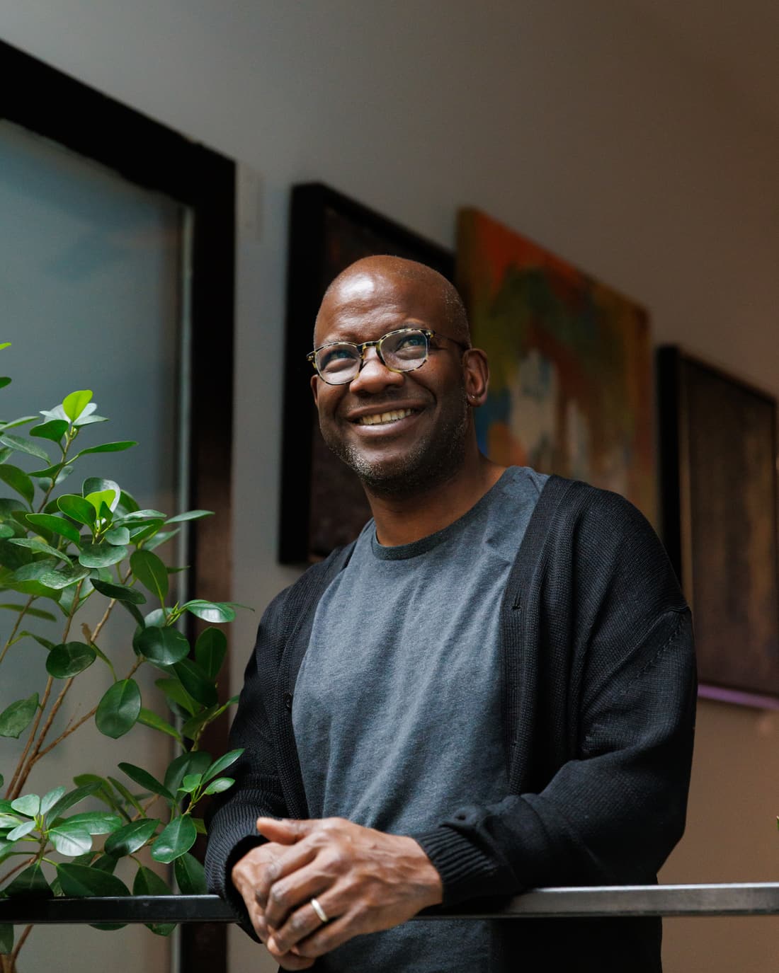 Quincy Goldsmith smiling beside a plant and framed artwork inside Stem & Vine in Baltimore