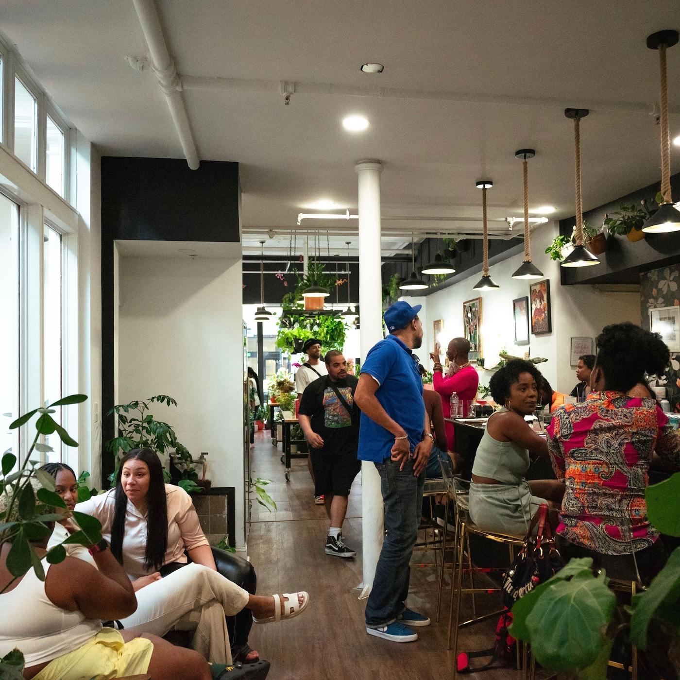 Guests spread along the long shop floor under pendant lights and hanging plants at Stem & Vine, Baltimore