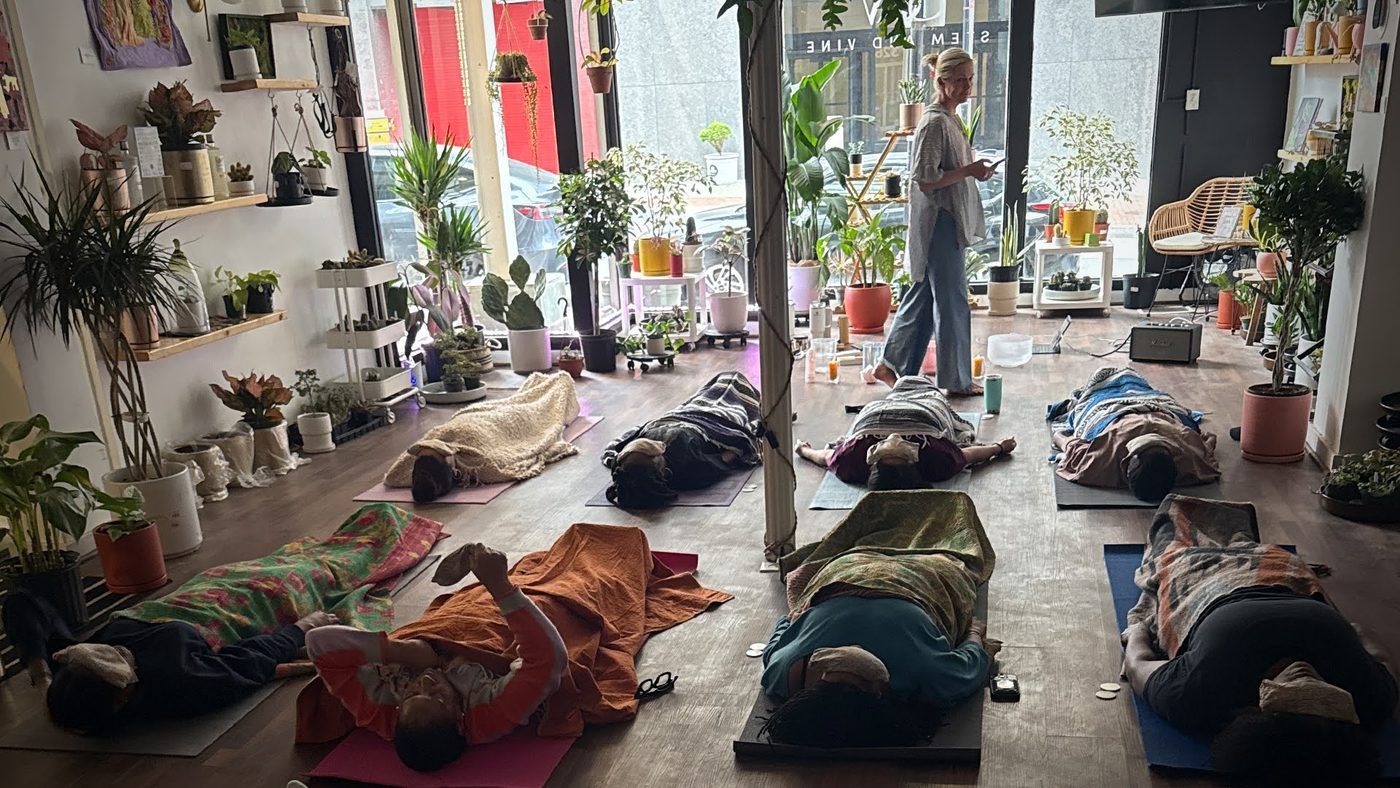 Guests resting on mats during a sound bath among the plants at Stem & Vine in Baltimore