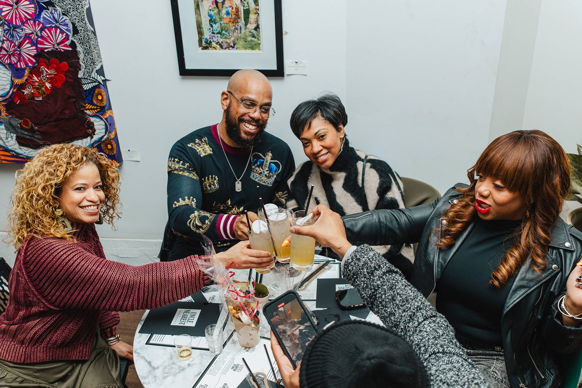Friends raising a toast during a whiskey tasting event at Stem & Vine in Baltimore