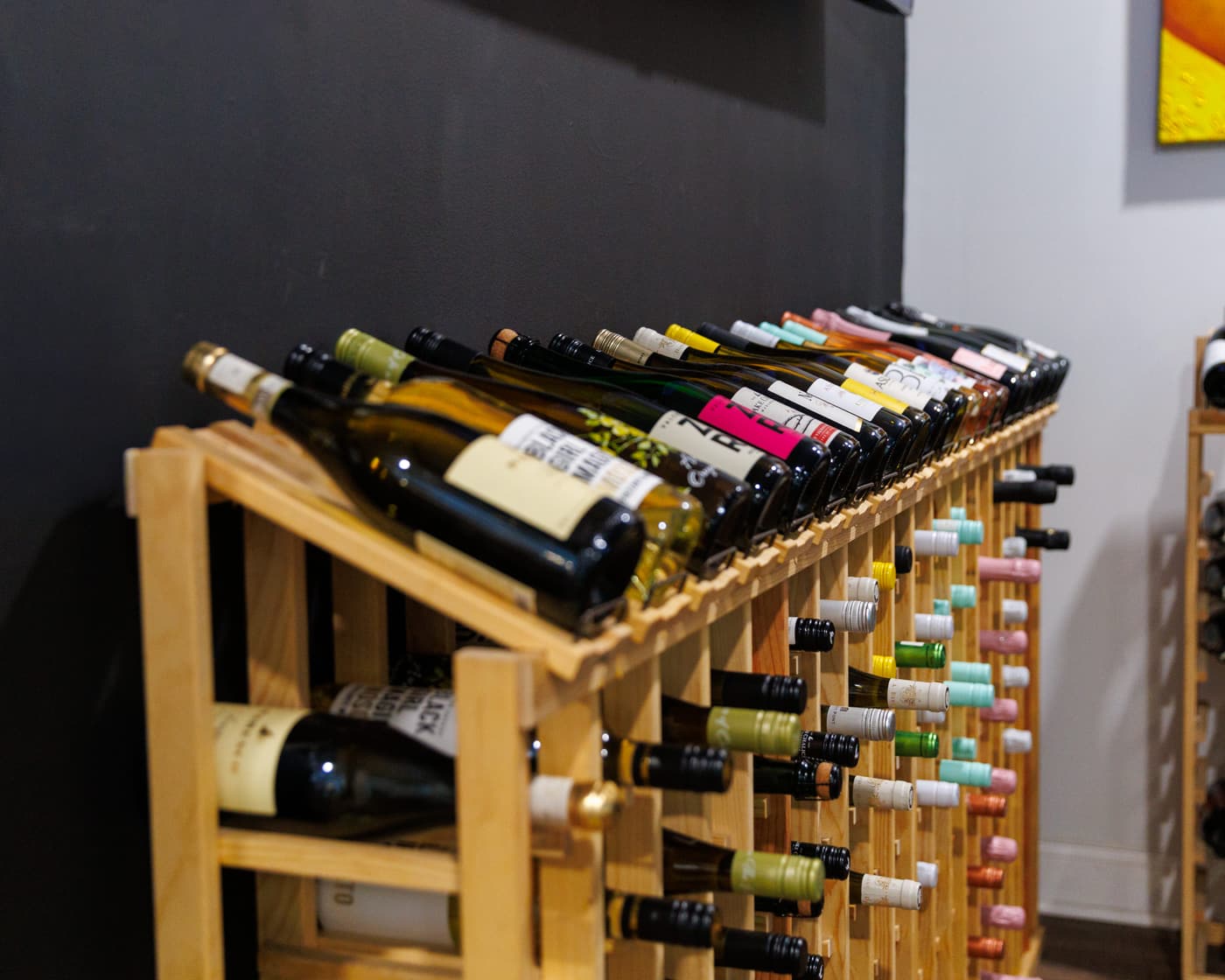 A wooden rack holding bottles of wine on their sides against a dark wall at Stem & Vine in Baltimore
